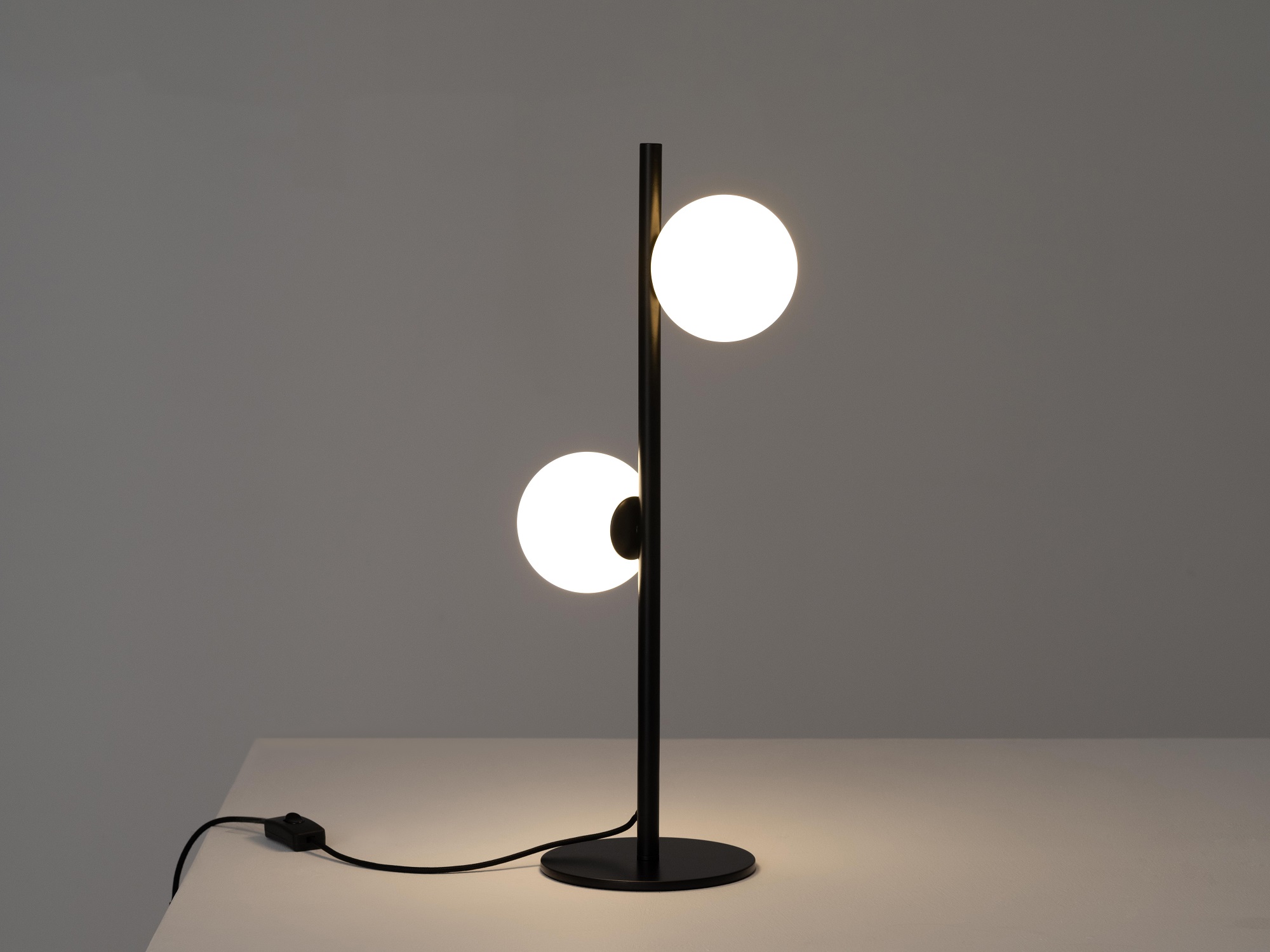 front view of the eq3 black stem table lamp turned on